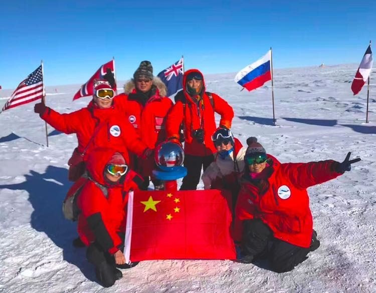 Polar expedition team photographed on snow with their base camp behind them