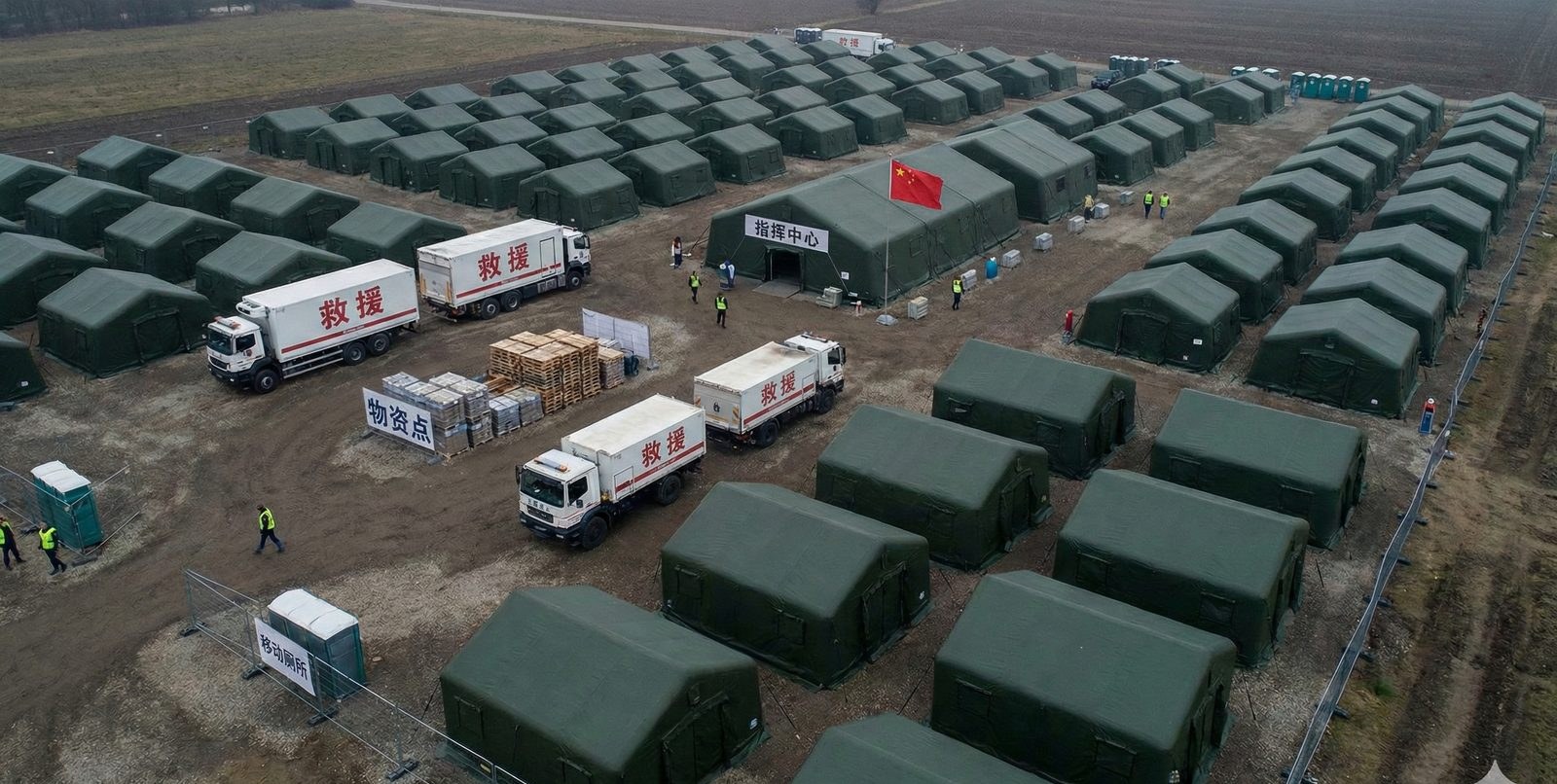 Aerial view of an emergency camp with a drone passing over rows of membrane units
